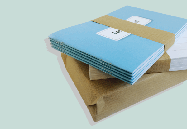 Gestapeltes Kairos Begleiter-Set von Rotmont mit mehreren blauen Coachingjournalen, seitlich gebündelt auf pastellfarbenem Hintergrund