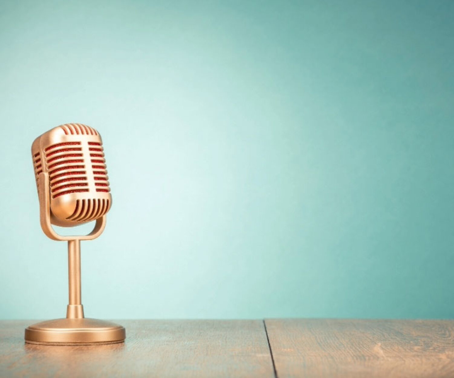 Goldenes Mikrofon auf Holz vor türkisem Hintergrund – Symbol für kreatives Interview mit Rotmont über Game Thinking.