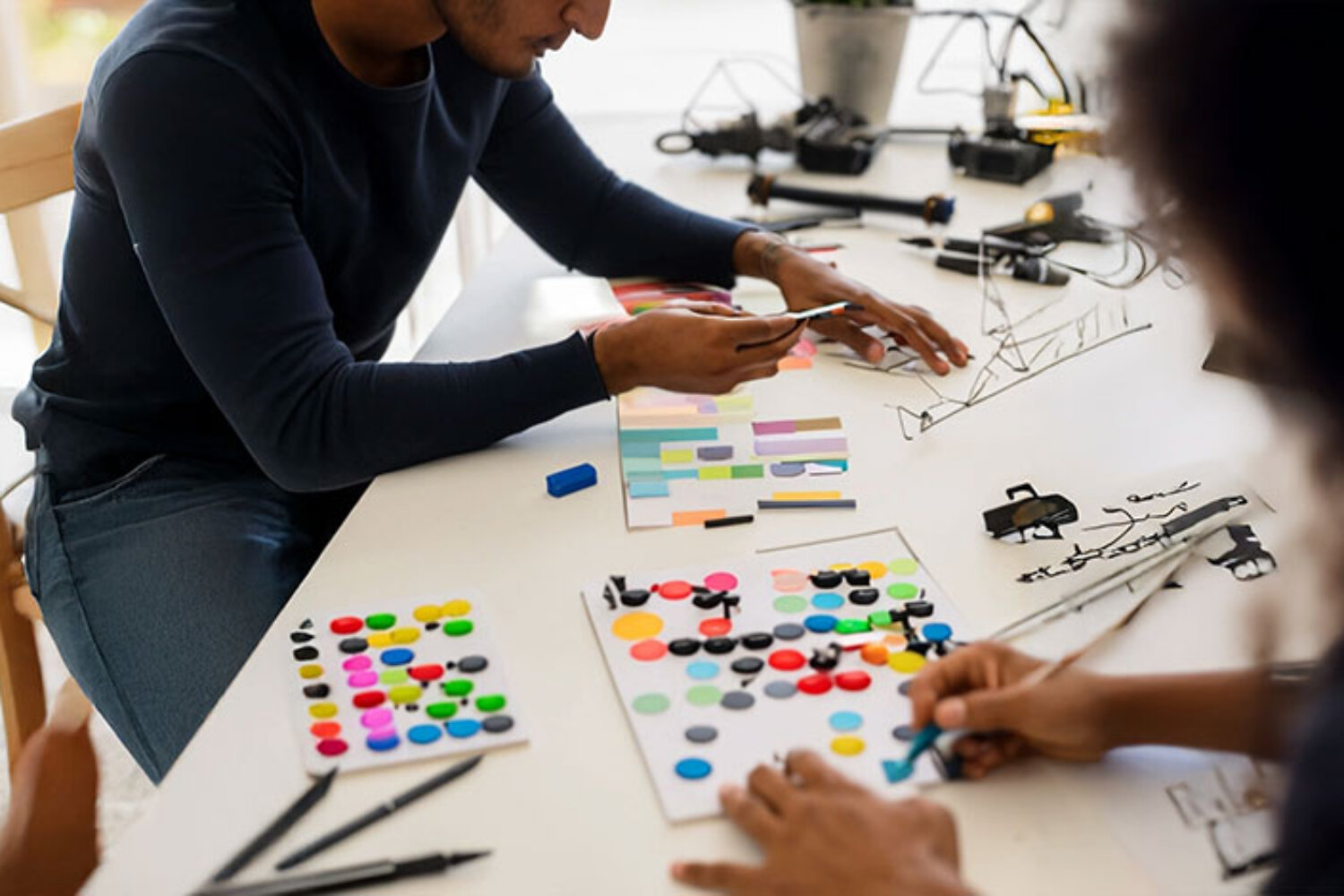 Menschen arbeiten gemeinsam mit Karten und Farben an einem Kreativprojekt – symbolisch für spielerische Projektentwicklung.