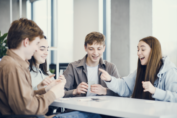 Drei Personen sitzen im Workshop zusammen am Tisch und arbeiten mit MIMI-Kartensets zu Teamkonflikten und Stärken