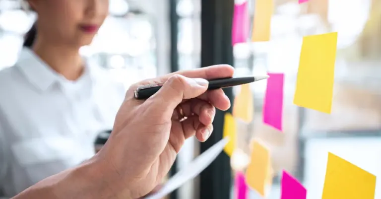 Hand zeigt auf Post-its zur Priorisierung
