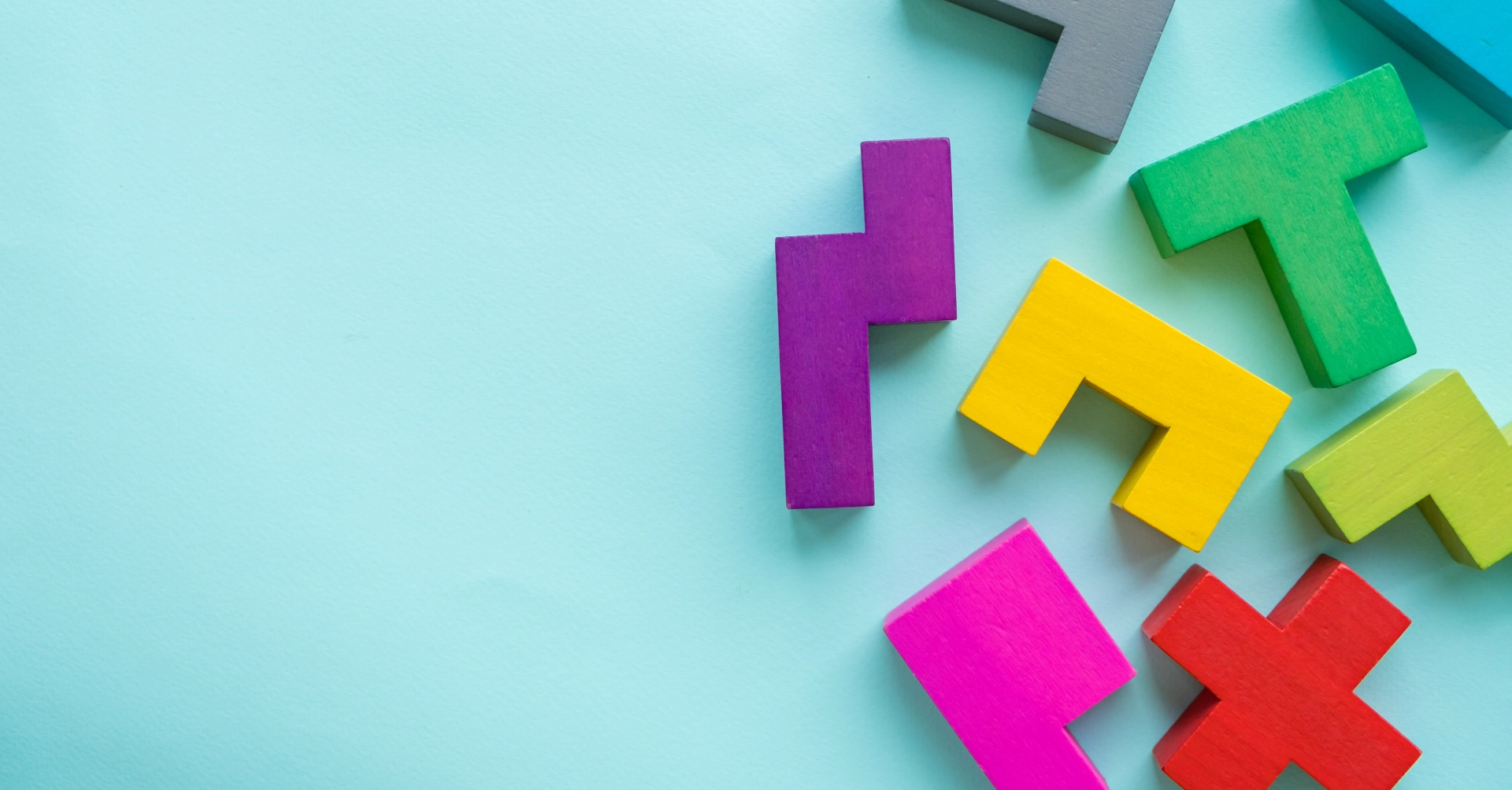 Farbige geometrische Spielsteine auf türkisfarbenem Hintergrund.